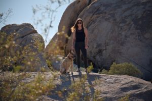 A woman standing with her dog on a hiking trip